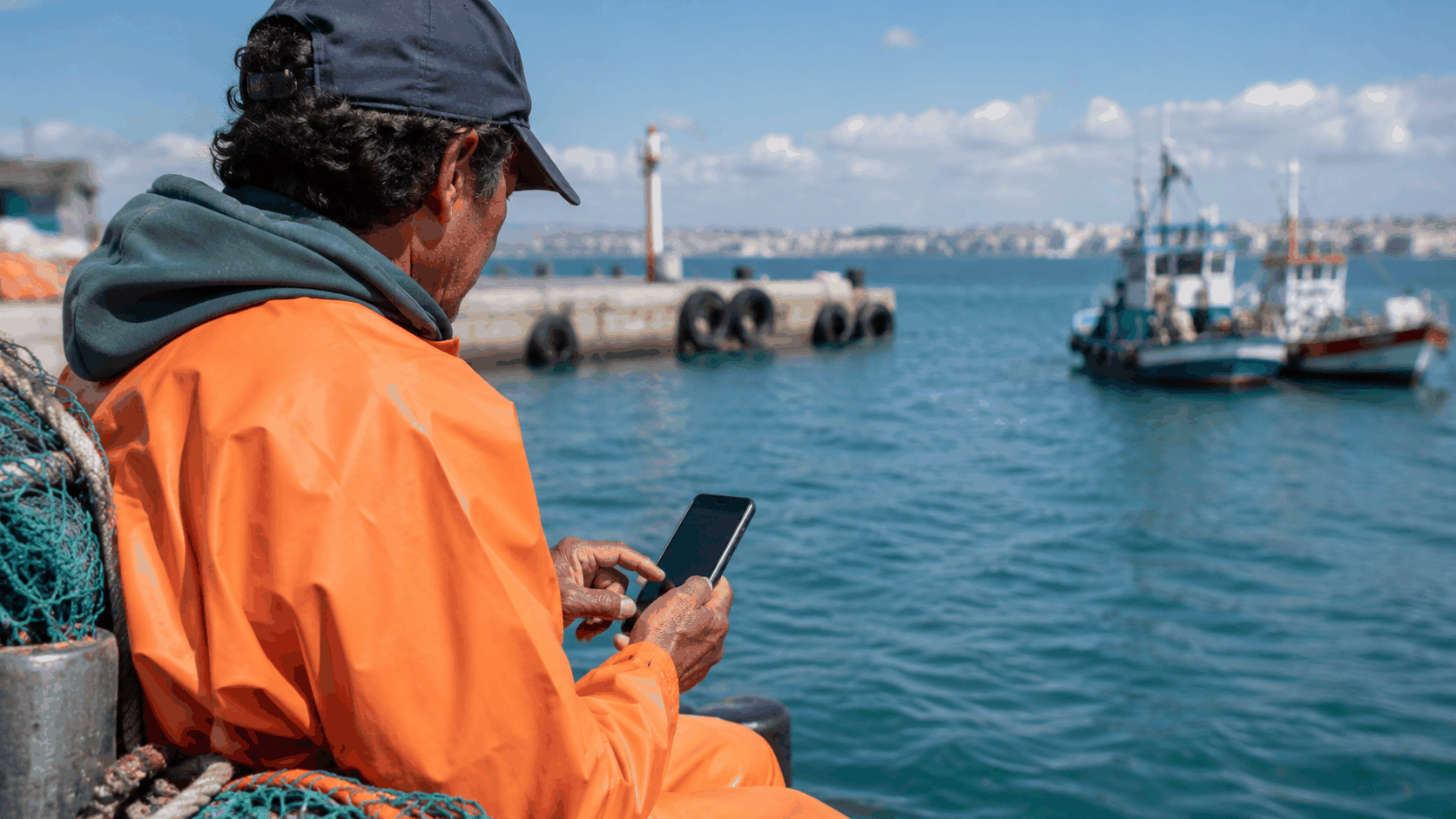 Pescador artesanal usando tecnología móvil en su jornada